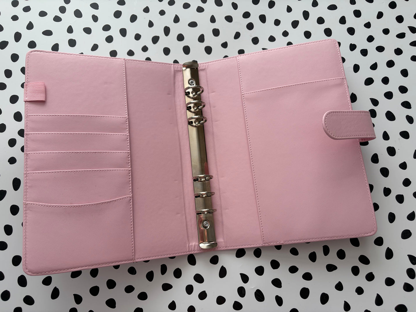 Pink planner with a metal ring binder on a polka dot background