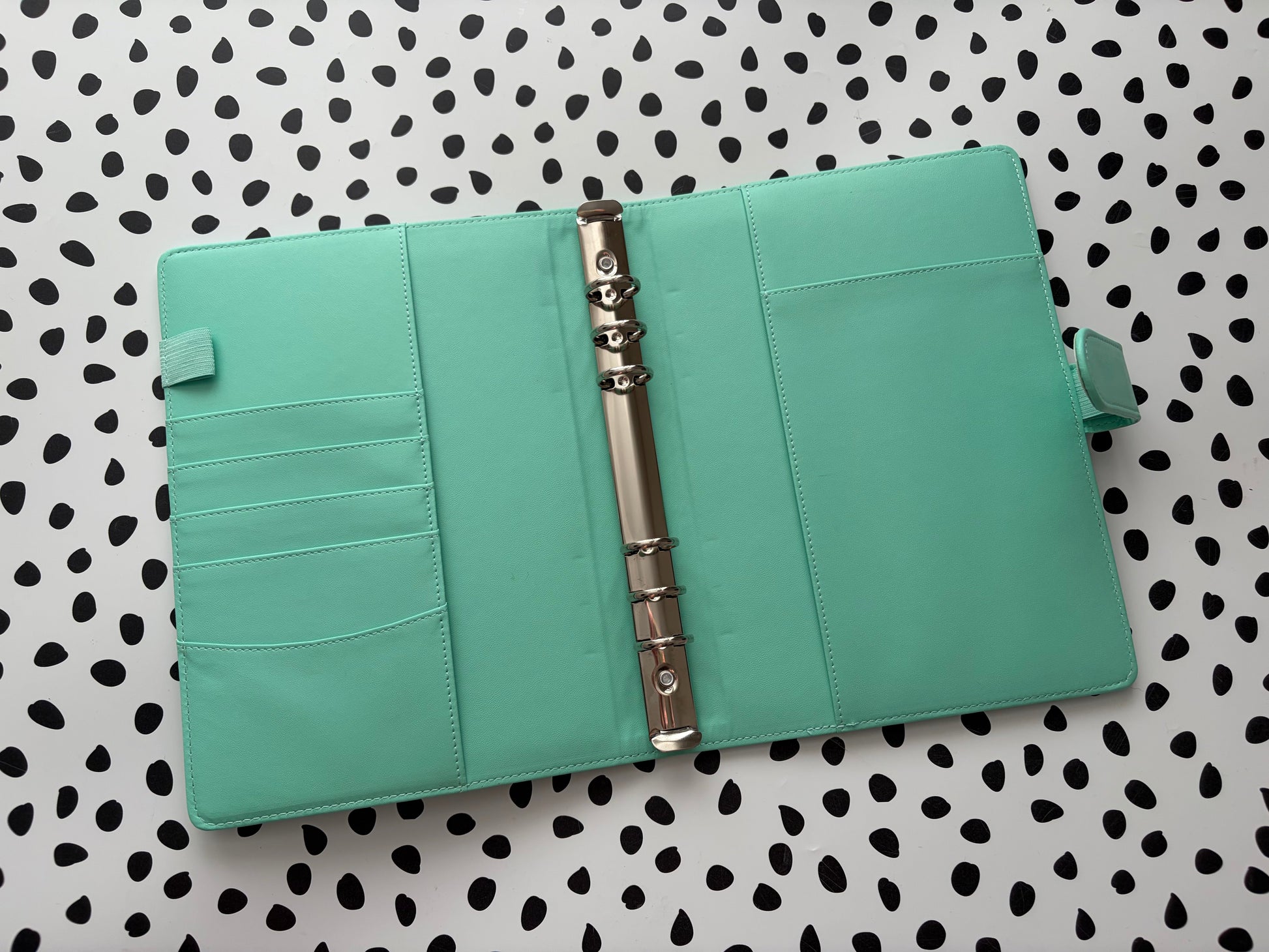 Turquoise planner with a metal binder clip on a polka dot background