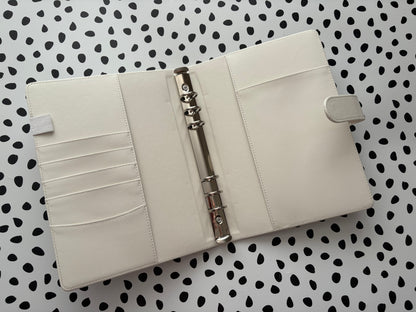 White planner with a metal ring binder on a polka dot background